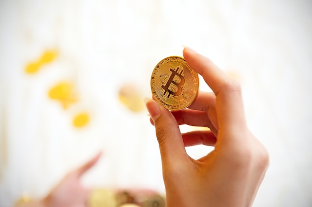Mano sosteniendo un token de bitcoin ¿para qué sirven las criptomonedas? 
