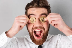 Hombre sonriente sostiene tokens de criptomonedas frente a sus ojos, representando una de las meme coin 2025