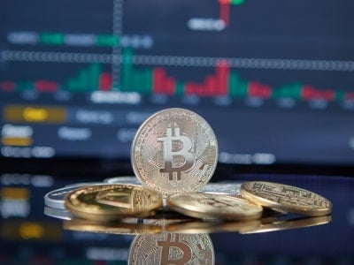 Bitcoins físicas delante de un gráfico de velas