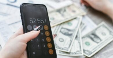 Persona con smartphone y billetes de dolares americanos