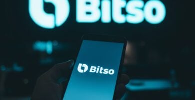 Persona con un smartphone con el logo de Bitso y una pantalla de fondo con el logo de Bitso
