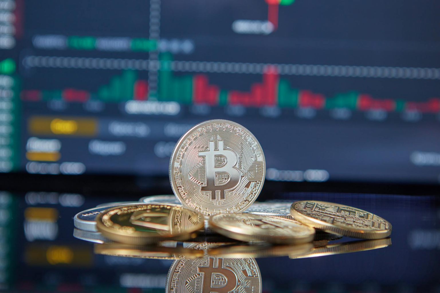 Representaciones físicas de las criptomonedas más importantes con un gráfico de velas de fondo