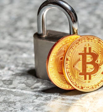 fotografia de un par de tokens de btc apoyados sobre un candado, representando si es seguro invertir en criptomonedas hoy en dia
