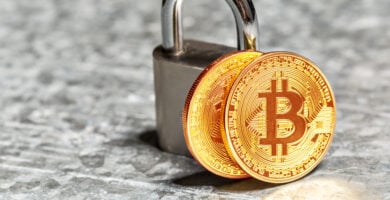 fotografia de un par de tokens de btc apoyados sobre un candado, representando si es seguro invertir en criptomonedas hoy en dia