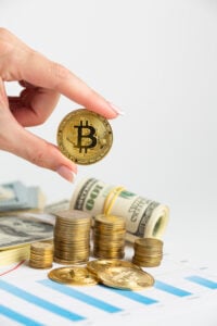 mano sosteniendo un token de btc al fondo billetes y monedas de dolar americanos