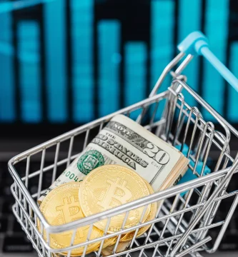 fotografia de un carrito de compras miniatura cargando un billete de dolar y un token de btc para respresentar por que la criptomoneda tiene valor