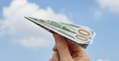 Persona sosteniendo un billete de cien dolares que envia la remesa.