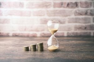 Son seguras las stablecoins​? Imagen de stcok pila de tokens en ascndente al lado de un reloj de arena 