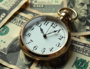 Un reloj de bolsillo sobre billetes de cien dolares
