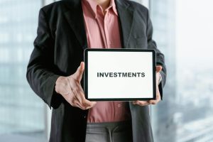 hombre sosteniendo pantalla con la palabra INVESTMENTS. Foto de stock representativa ¿Cómo analizar un whitepaper antes de invertir?
